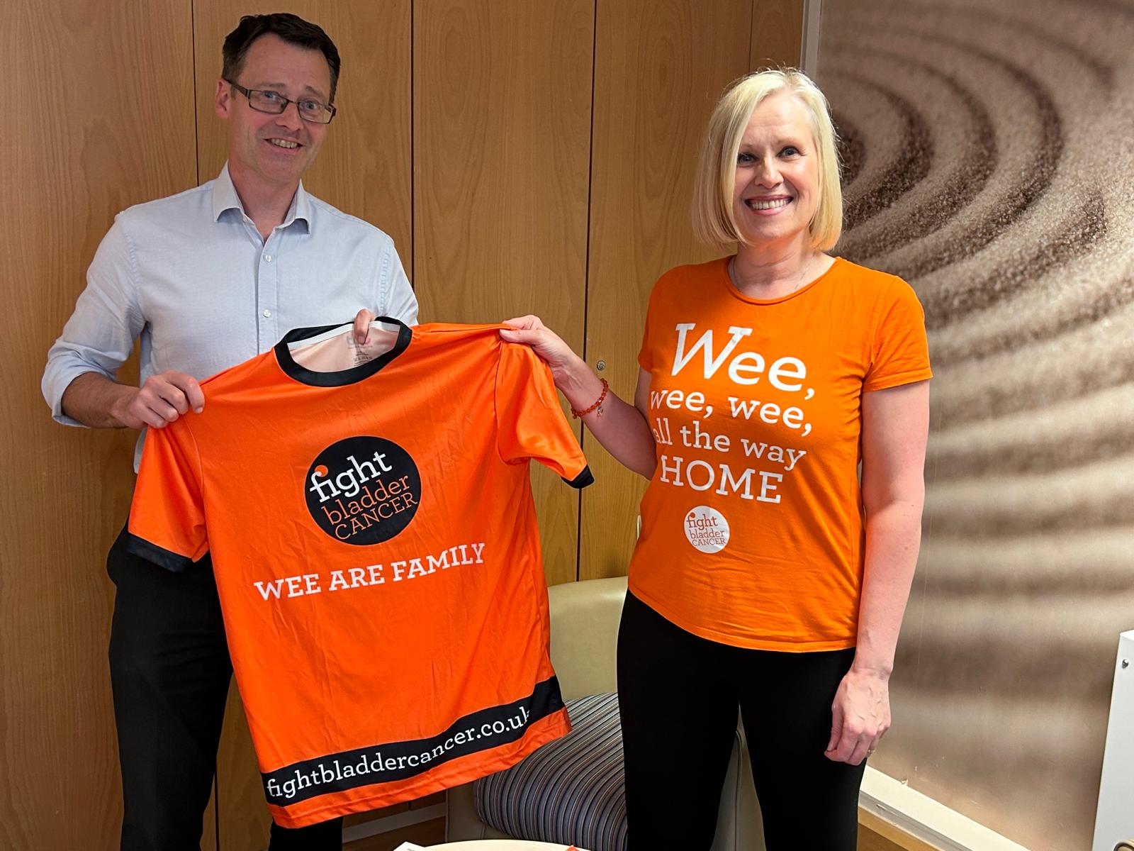 Photo of Silas Nicholls and Alison Birtle holding an orange campaign t-shirt