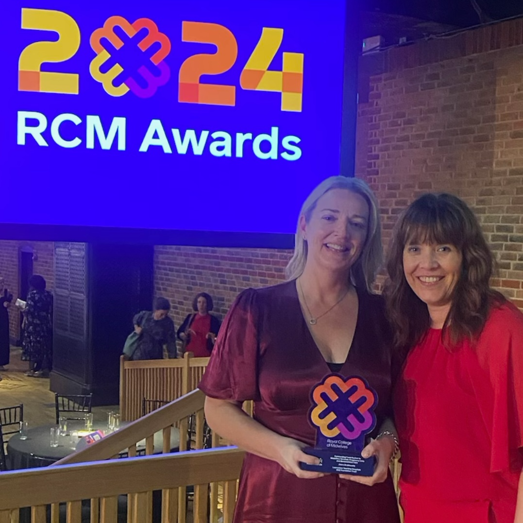 Photo of Claire and a friend as Claire holds the reward plaque