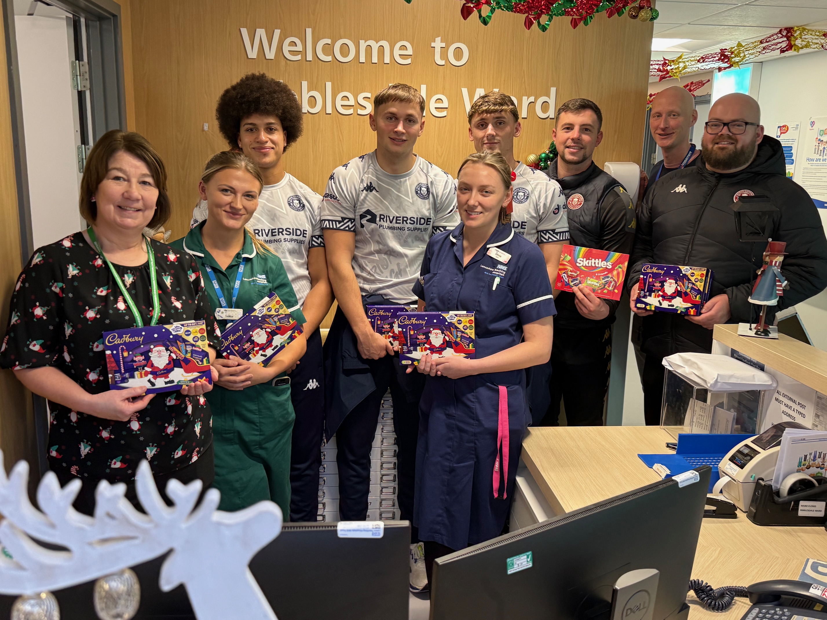 Wigan Warriors athletes pictured with NHS staff and holding Christmas gifts