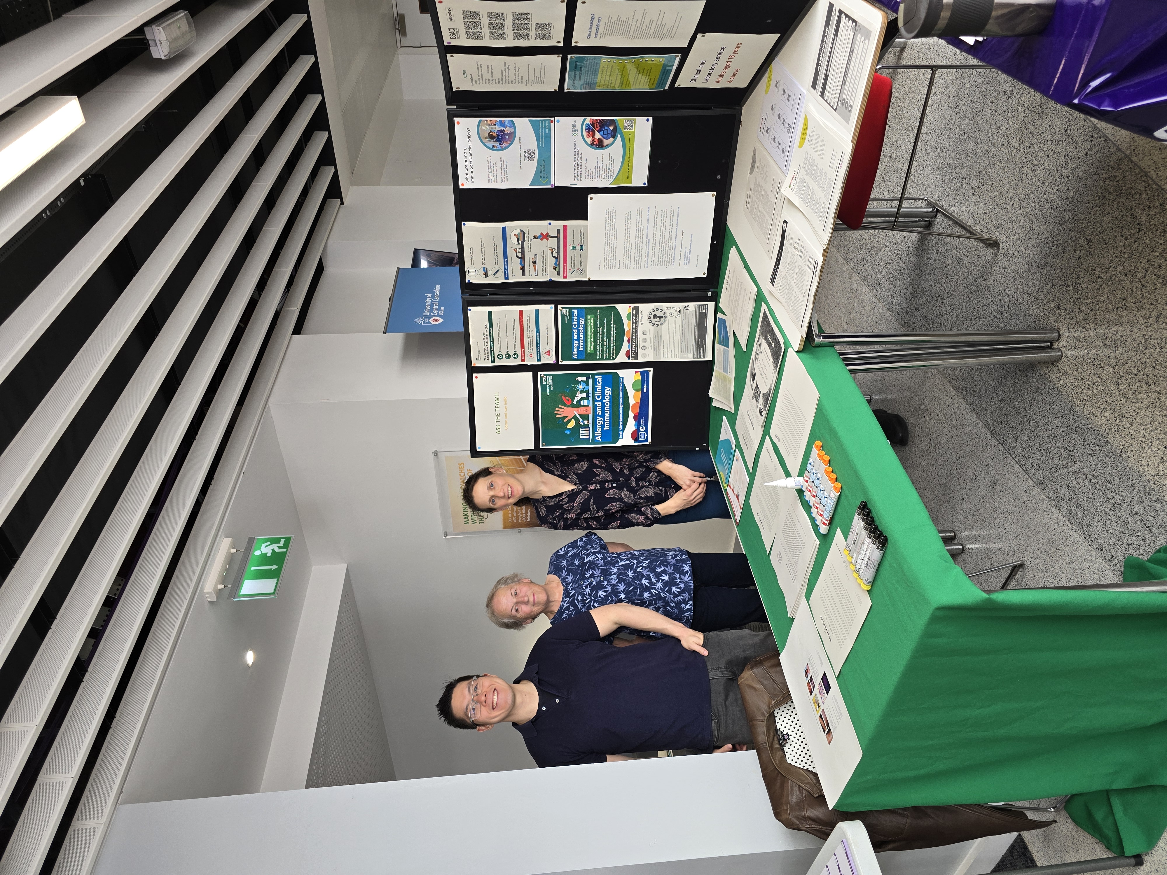 Photo of staff members next to Health Mela table covered with information leaflets