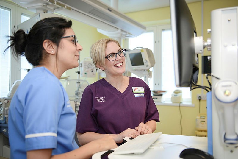 Photo of two NHS professionals, in uniform, looking at a monitor